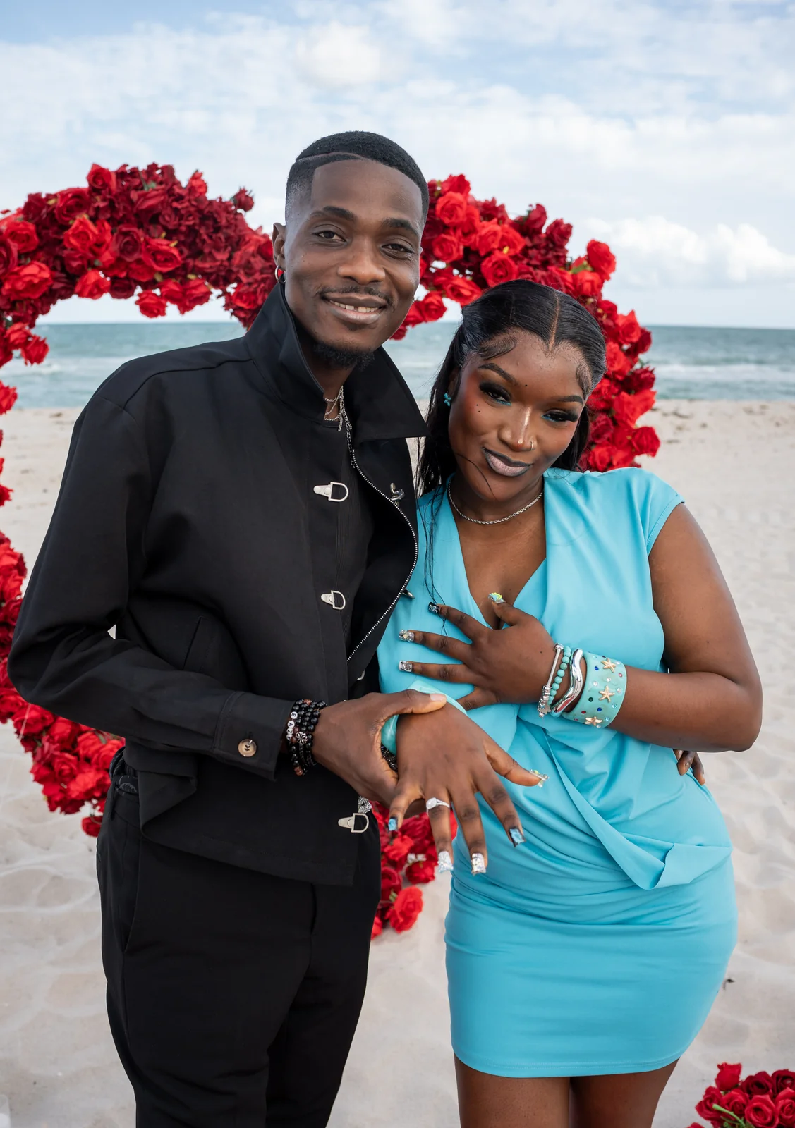 The newly engaged couple stands together by the ocean.